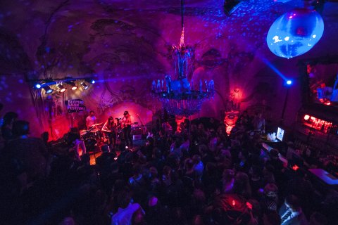 Eine kleine Bühne in einem dunklen Club beim Reeperbahnfestival 2016. Mit Publikum, großen Kronleuchter und bunter Beleuchtung.